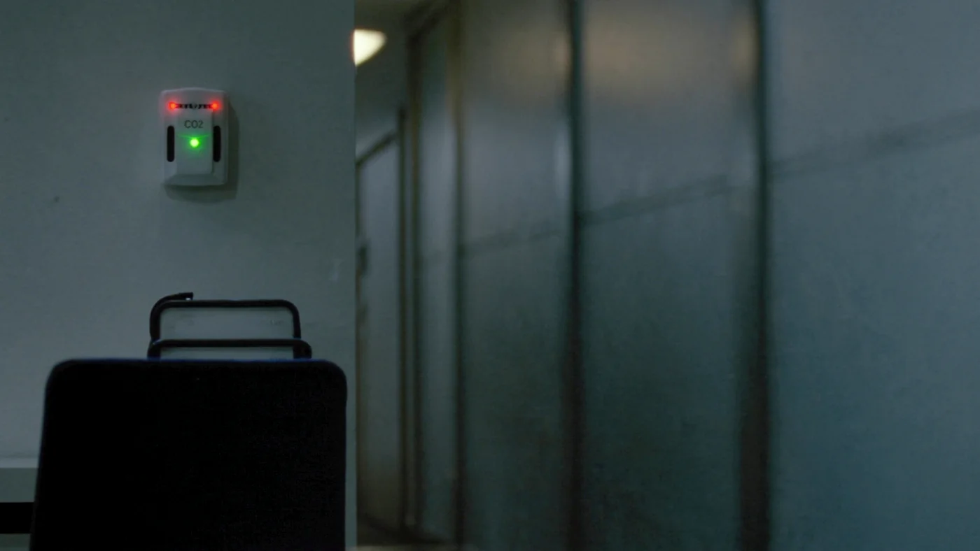 A wall-mounted CO2 sensor in an empty meeting room, evening light