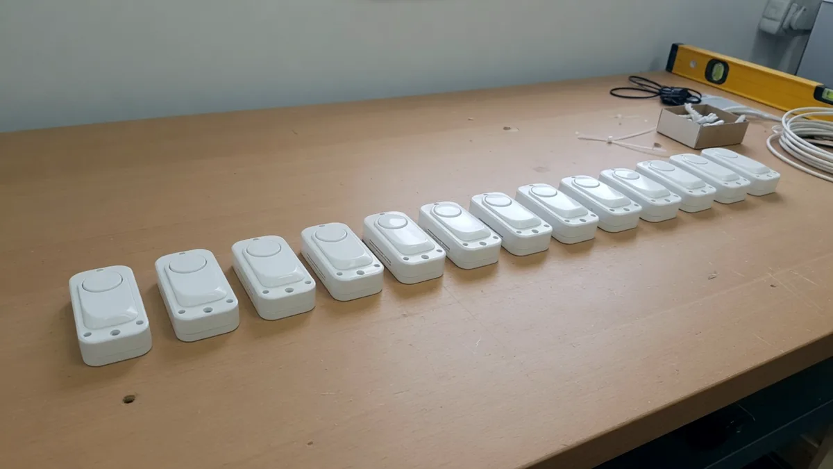 A row of identical small white wireless sensors laid out on a workbench